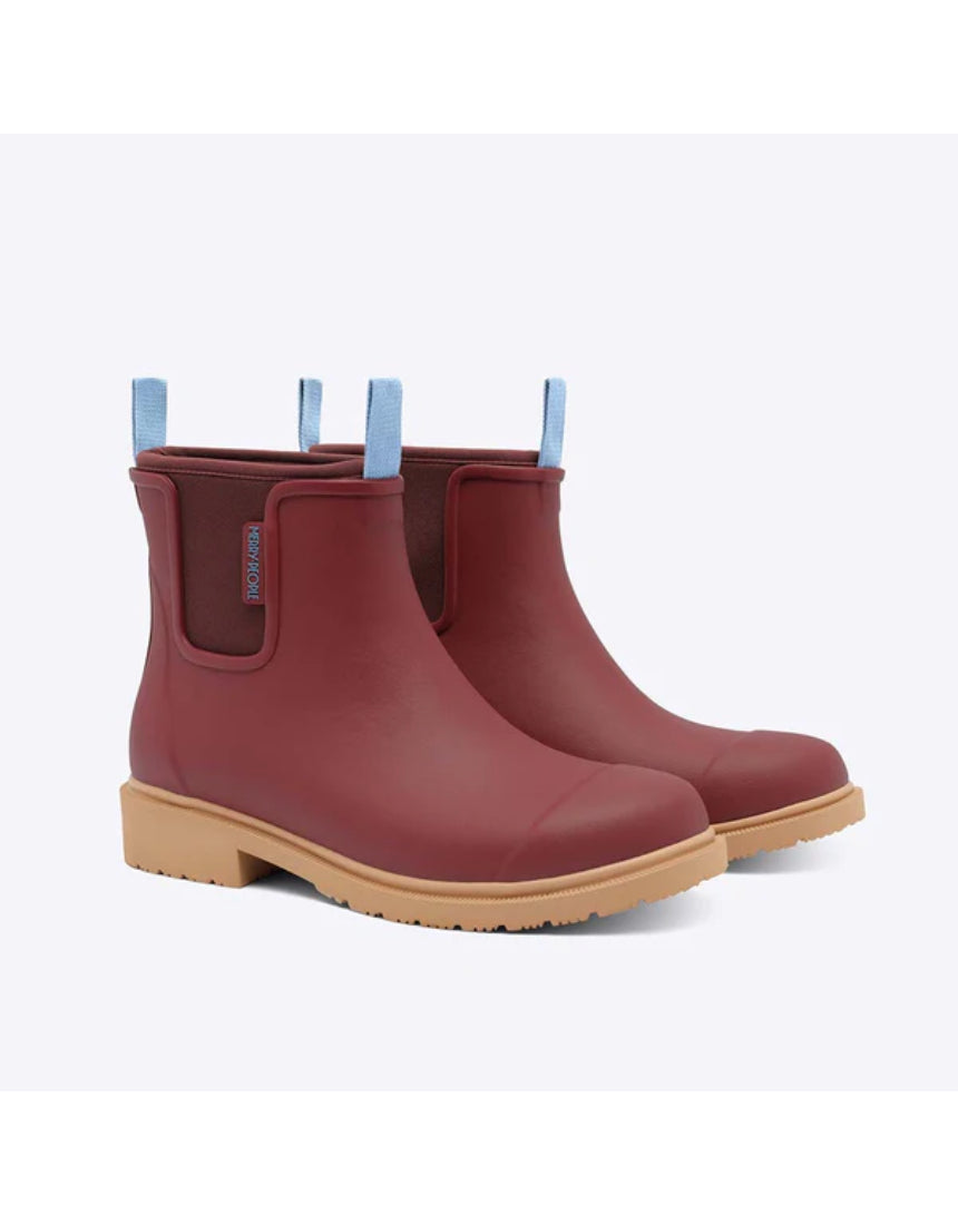 Brick red Merry People Bobbi gumboots with black sole and rounded toe, stylish waterproof footwear for rainy days.