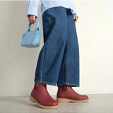 Brick red Merry People Bobbi gumboots worn by a model, showcasing stylish waterproof rubber footwear for rainy days.