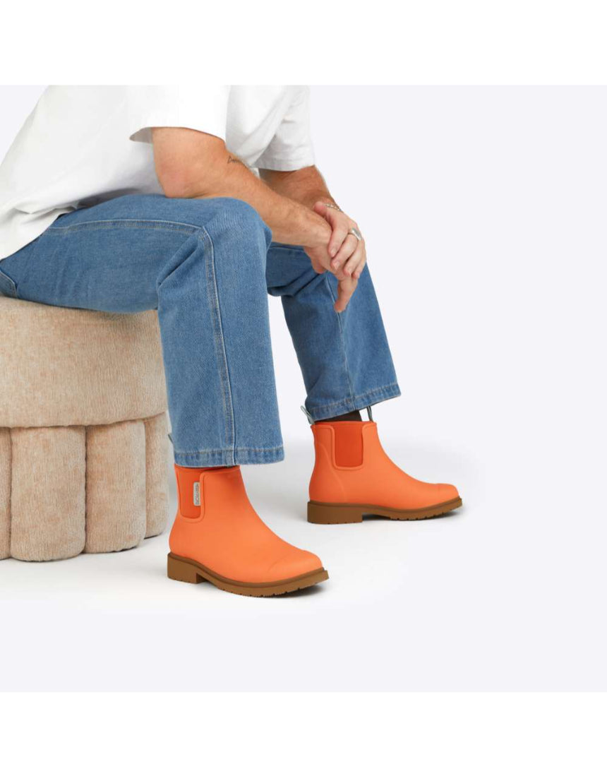 Merry People Bobbi gumboots in sherbet orange, stylish waterproof rain boots with a sleek design, shown sitting on a white background.