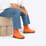 Merry People Bobbi gumboots in sherbet orange, stylish waterproof rain boots with a sleek design, shown sitting on a white background.