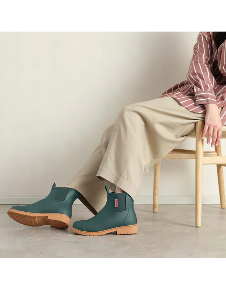 Merry People Bobbi gumboots in teal worn by a model, showcasing waterproof rubber footwear for outdoor wear.