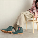 Merry People Bobbi gumboots in teal worn by a model, showcasing waterproof rubber footwear for outdoor wear.