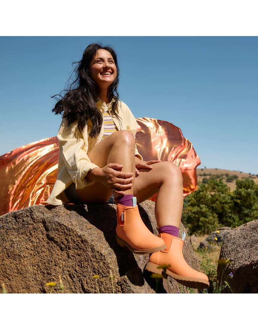 Merry People Bobbi gumboots in vibrant sherbet orange, showcasing a stylish waterproof footwear design for rainy days.