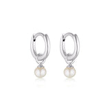 Linda Tahija Pearl Charm Mini Huggie Earrings featuring small gold hoops with delicate pearl charms on a white background.