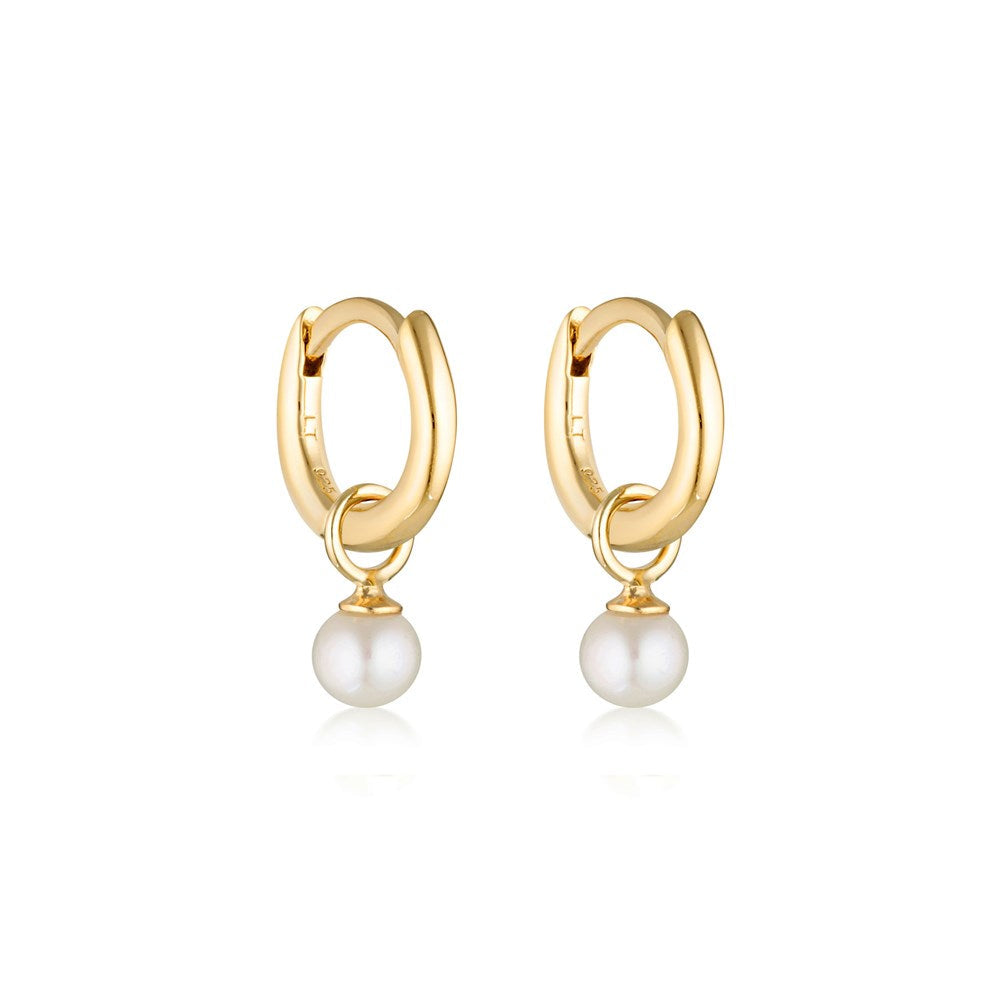 Linda Tahija pearl charm mini huggie earrings featuring small gold hoops with dangling pearl accents.