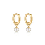 Linda Tahija pearl charm mini huggie earrings featuring small gold hoops with dangling pearl accents.