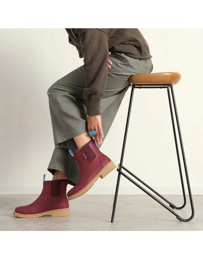 Brick red Merry People Bobbi gumboots on a model, showcasing stylish waterproof footwear for rainy weather.