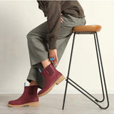 Brick red Merry People Bobbi gumboots on a model, showcasing stylish waterproof footwear for rainy weather.