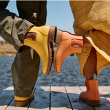 Merry People Bobbi gumboots in vibrant sherbet orange, stylish waterproof rain boots for women, shown outdoors in a lifestyle shot.