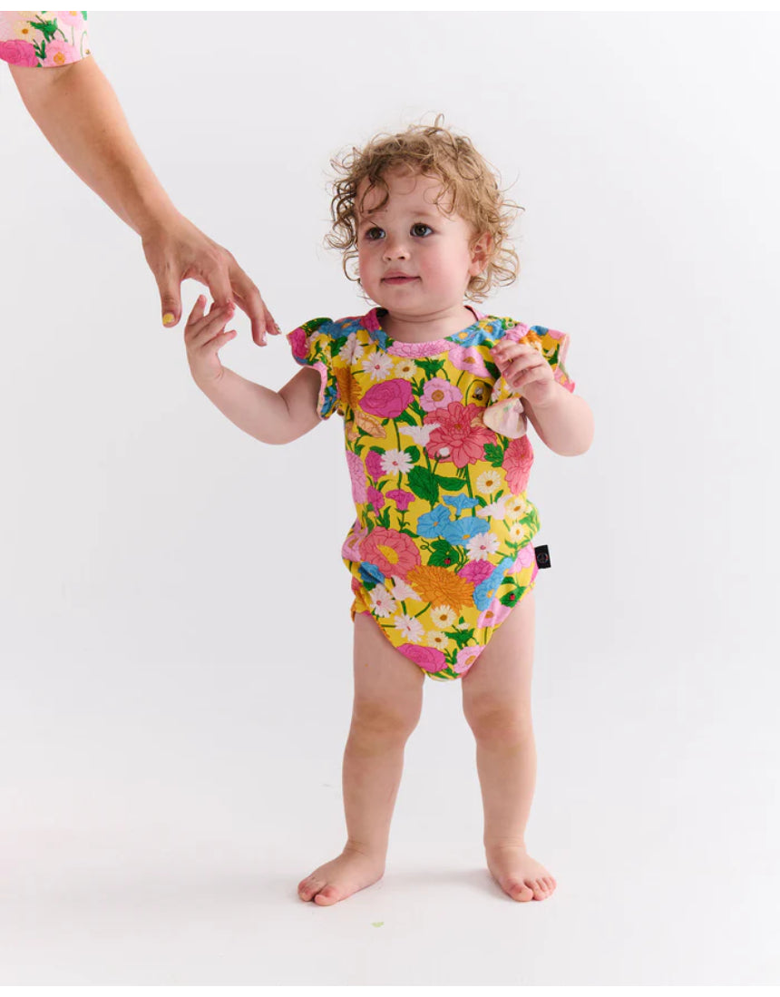 Kip & Co baby girl short sleeve frill romper with sun-themed pattern, soft fabric, and cute ruffle details.