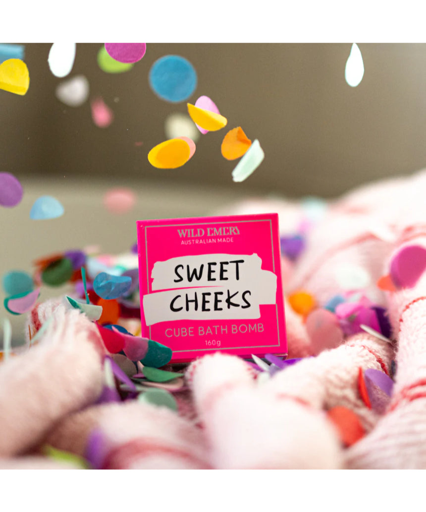 Wild Emery Sweet Cheeks Bath Bomb from the Bath & Body collection, showing a colorful, round bath bomb with a textured surface.