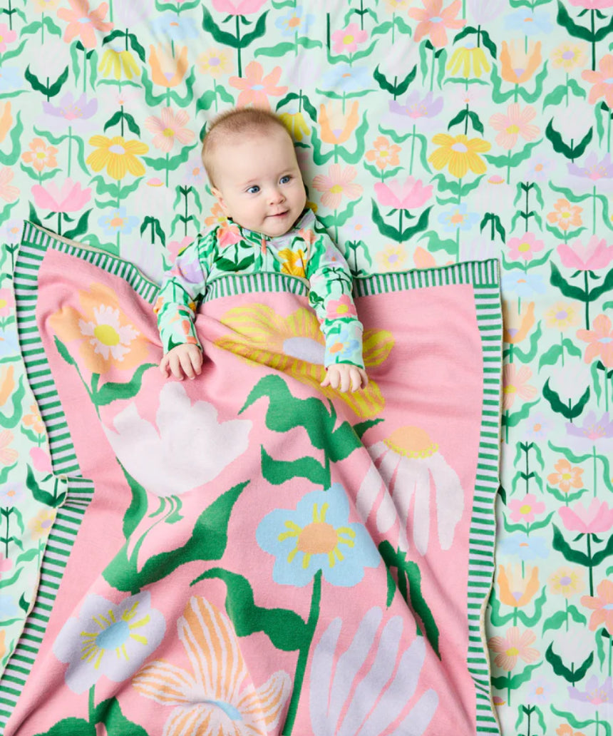 Kip & Co green cotton knitted blanket with vibrant flower pattern, soft and cozy for sofa or bed.