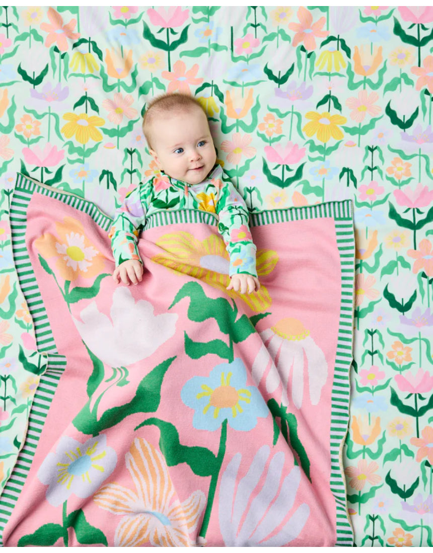 Kip & Co green cotton knitted blanket with vibrant flower pattern, soft and cozy for sofa or bed.