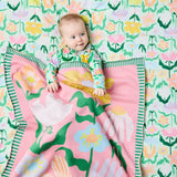 Kip & Co green cotton knitted blanket with vibrant flower pattern, soft and cozy for sofa or bed.