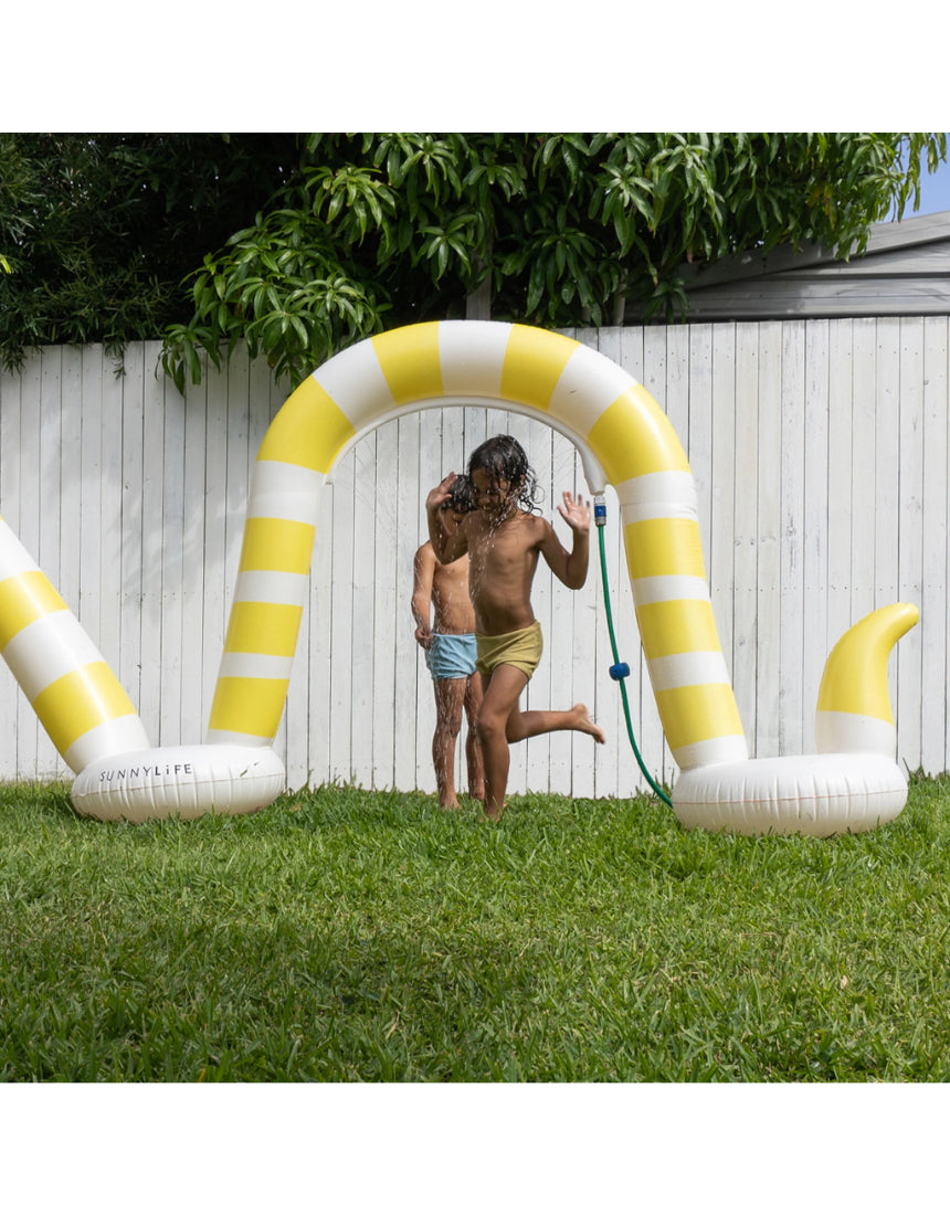 Sunnylife Snake Giant Sprinkler outdoors, colorful inflatable snake-shaped garden sprinkler with water spraying from its head.