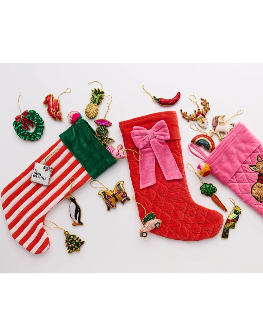 Kip & Co Christmas Bow Velvet Stocking hanging as a festive holiday decoration with red and green velvet details.