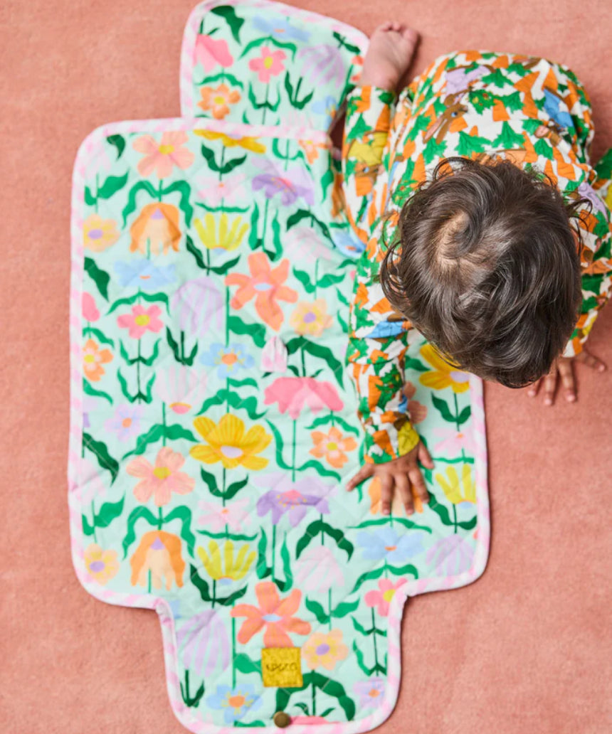 Kip & Co Popping Flowers green baby change mat with floral print, padded surface, and secure straps for comfortable changing.
