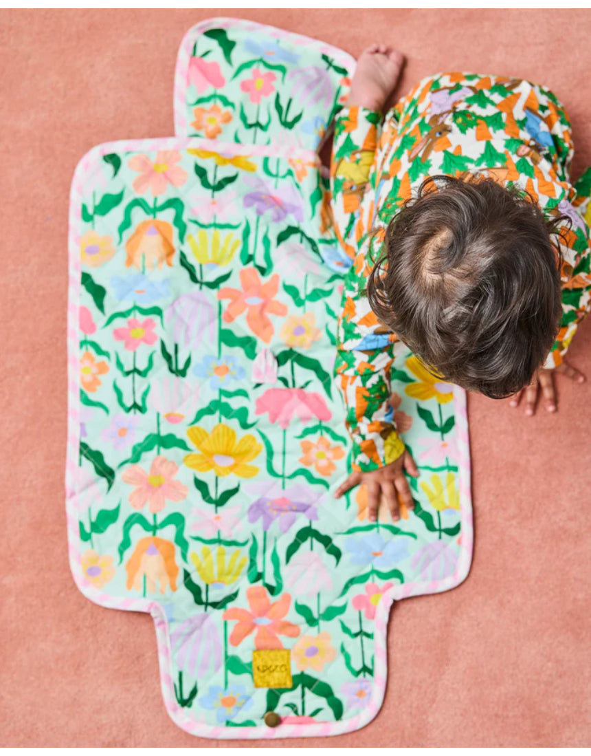 Kip & Co Popping Flowers green baby change mat with floral print, padded surface, and secure straps for comfortable changing.