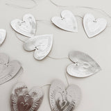 Reversible faux-tin heart bunting in light dusty pink by THE LITTLE PRESS, featuring hanging heart shapes for decorative use.
