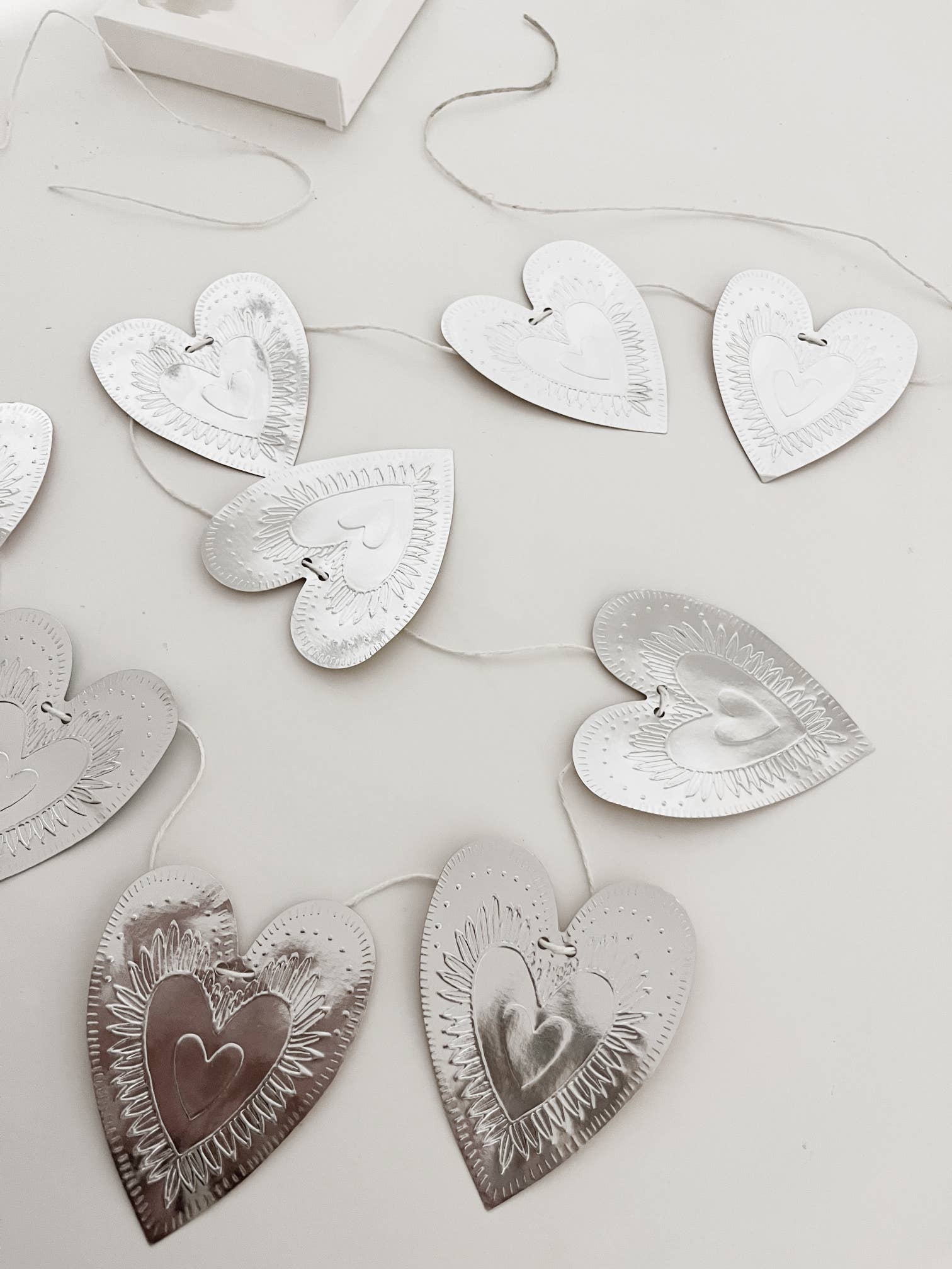 Reversible faux-tin heart bunting in light dusty pink by THE LITTLE PRESS, featuring hanging heart shapes for decorative use.