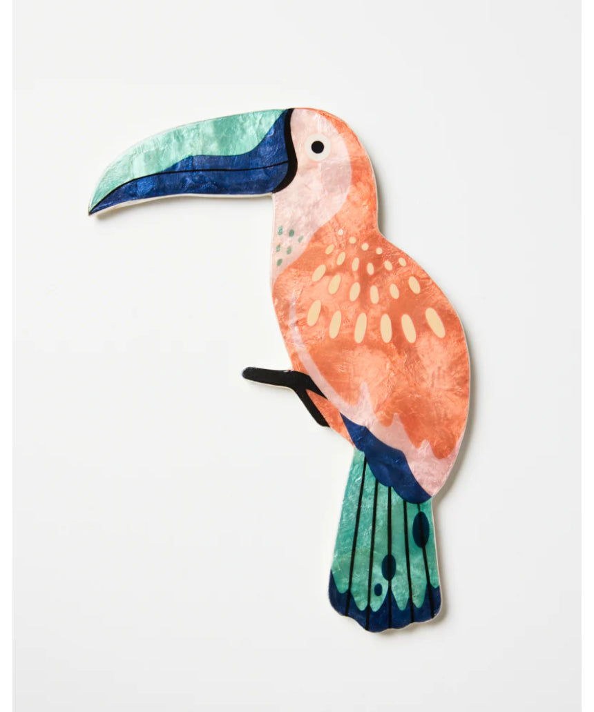 Jones & Co Canopy Toucan Peach wall art featuring a colorful toucan perched among tropical foliage on a peach background.