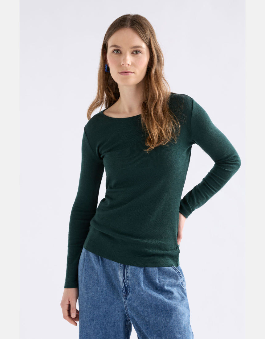 Elk Merino long sleeve top in dark pine color, lightweight and soft, shown on a hanger with a close-up of the fabric texture.