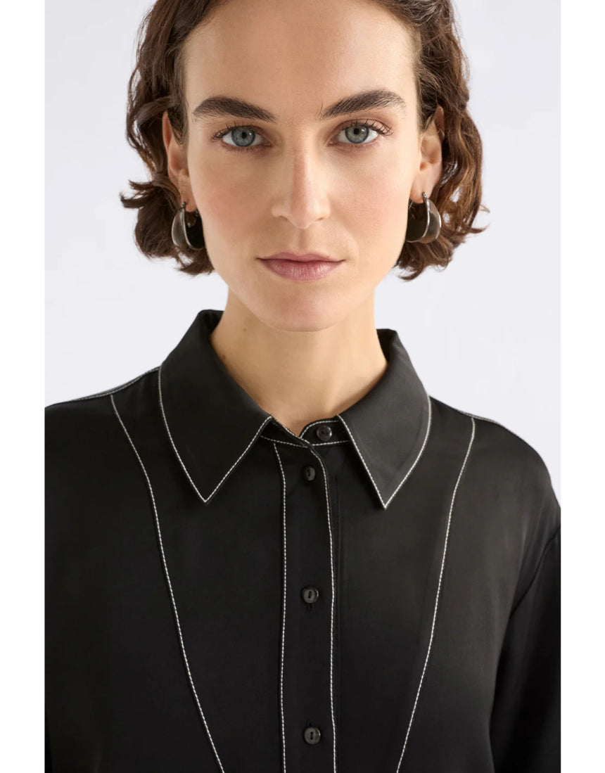 Black Elk Famke Dress hanging on a wooden hanger, showcasing its elegant design and fabric details.