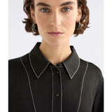 Black Elk Famke Dress hanging on a wooden hanger, showcasing its elegant design and fabric details.