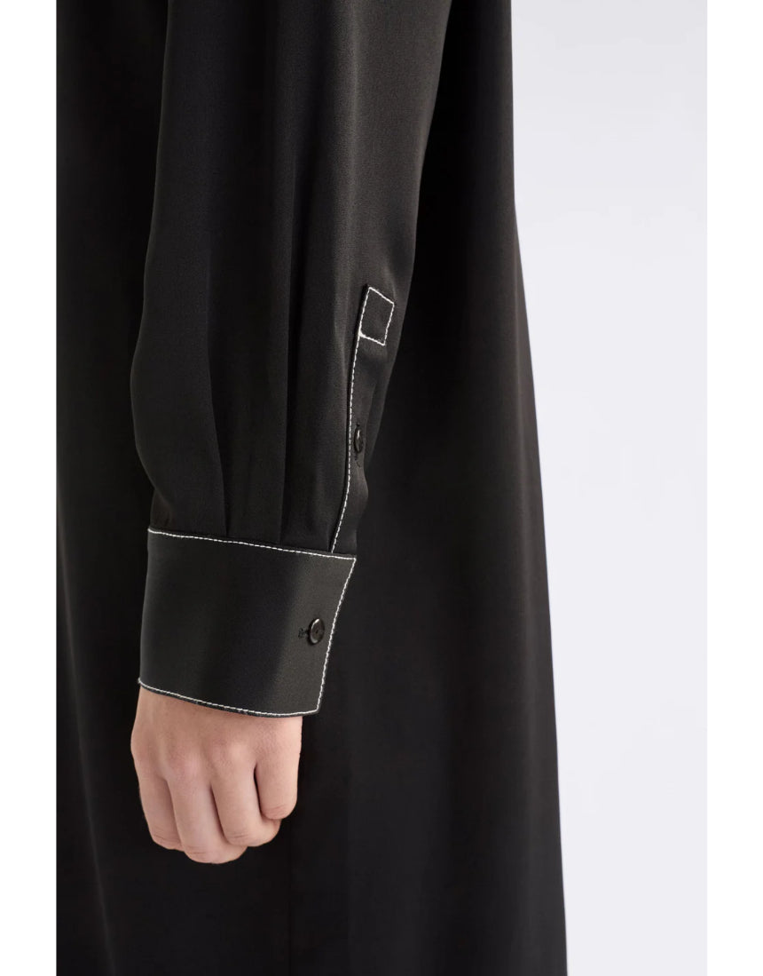 Black Elk Famke Dress displayed on a hanger, showcasing its stylish design and fabric details.