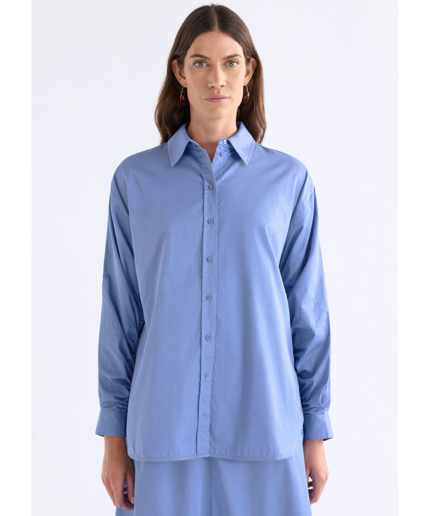 ELK The Label Dusk Blue Sol Shirt, a stylish blue top with a relaxed fit, displayed on a hanger.