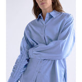 Dusk blue Elk Sol Shirt from ELK The Label, a stylish women's top with a relaxed fit and soft fabric, shown on a hanger.