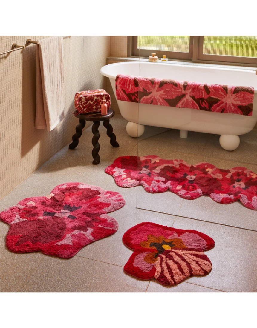 Pink long bath mat by Bonnie and Neil featuring a soft, textured design with a floral pansy pattern.