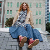 Merry People Bobbi gumboots in brick red, outdoor lifestyle image showing waterproof rubber boots on a person walking in a muddy area.