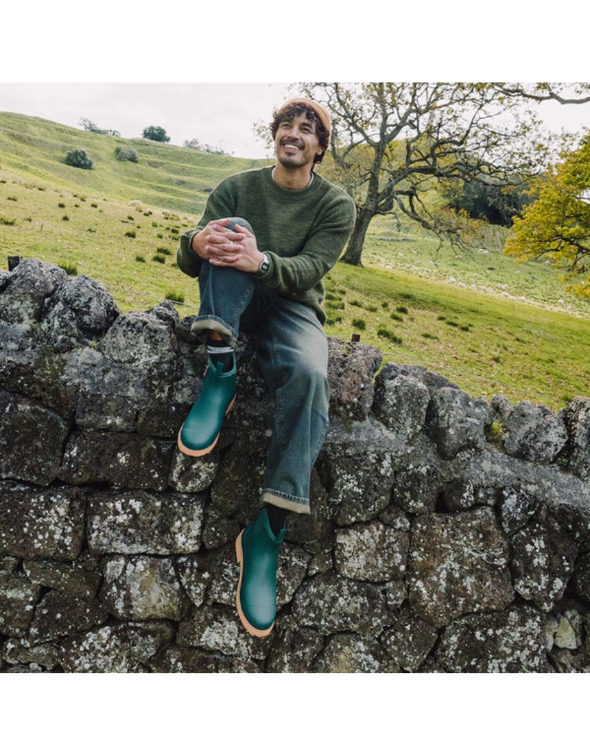 Merry People Bobbi Gumboots in teal, stylish waterproof rain boots for women, shown in a lifestyle outdoor scene.