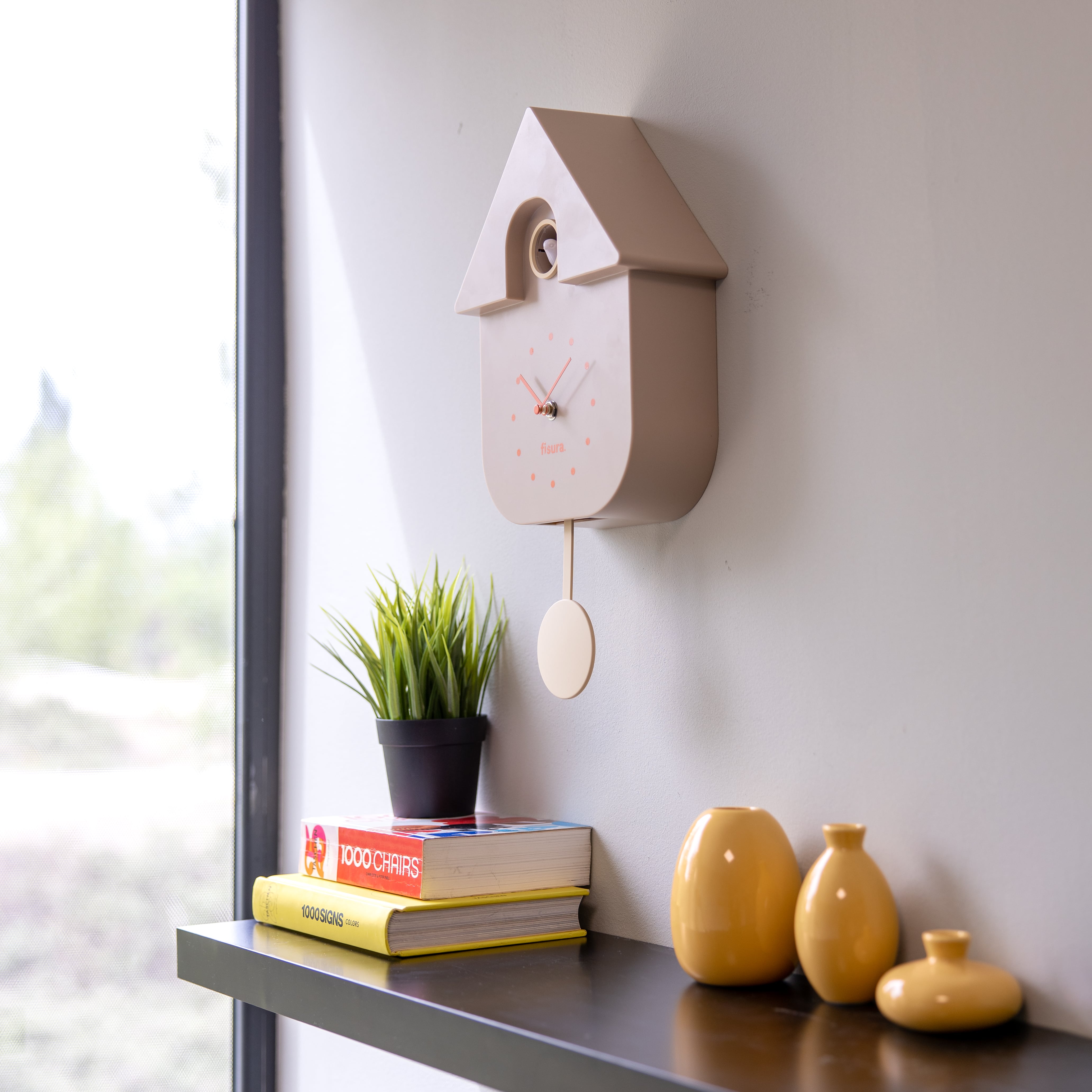 Beige Fisura cuckoo clock with traditional design, featuring a wooden case and clock face with Roman numerals.