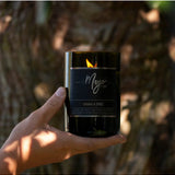 Mojo Candle Co. Cognac & Spice Black Label candle in a dark glass jar with a lit wick, emitting a warm, spicy glow.