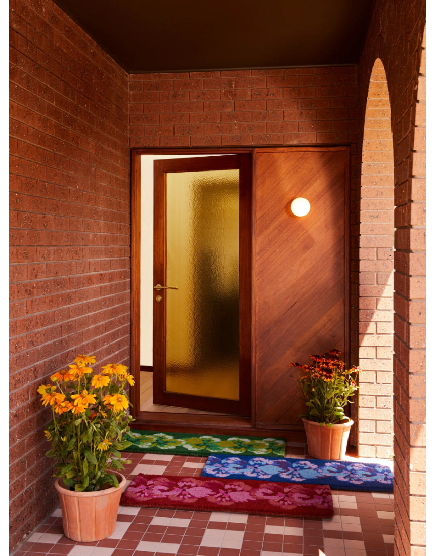 Pink coir door mat featuring a pansy flower design by Bonnie and Neil, ideal for welcoming entryways.
