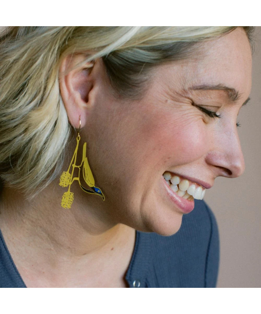 Blue Faced Honeyeater earrings by Denz featuring honey, blue, and black colors with intricate design, worn as stylish jewelry.