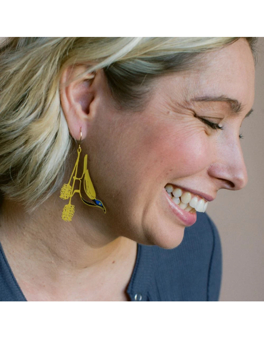 Blue Faced Honeyeater earrings by Denz featuring honey, blue, and black colors with intricate design, worn as stylish jewelry.