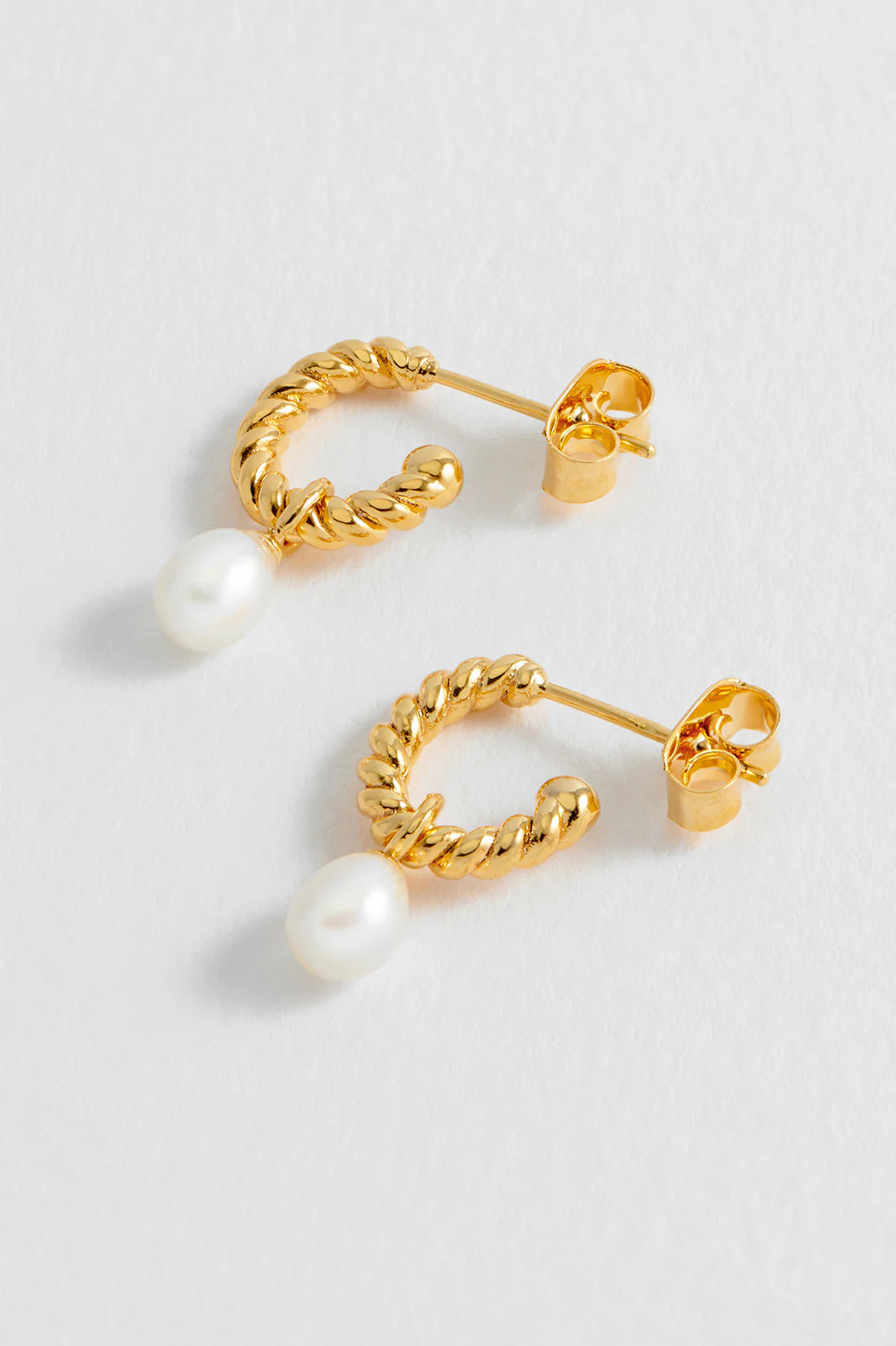 Estella Bartlett pearl drop and twist hoop earrings with elegant design and shiny metal finish.
