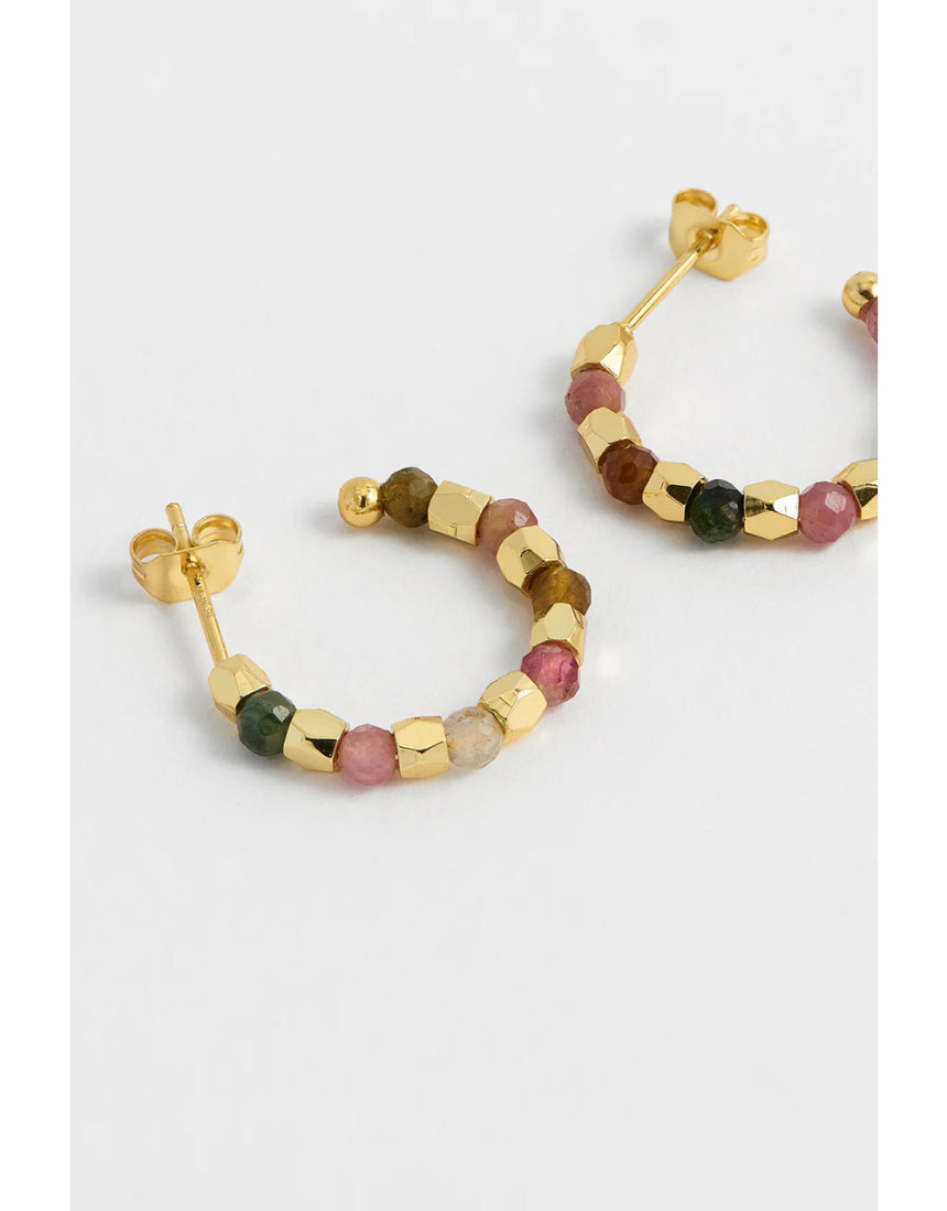 Gold hoop earrings by Estella Bartlett featuring coco and tourmaline accents, displayed on a neutral background.