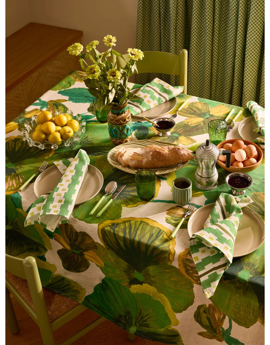 Bonnie and Neil Gem Green glass tumbler with a smooth surface, shown on a dining room table setting.