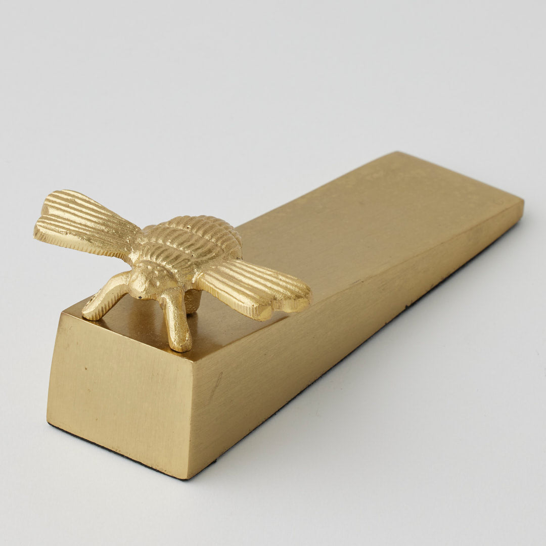 Gold Pilbeam Living Bee Door Wedge with detailed bee design and sturdy wedge shape for keeping doors open or closed.