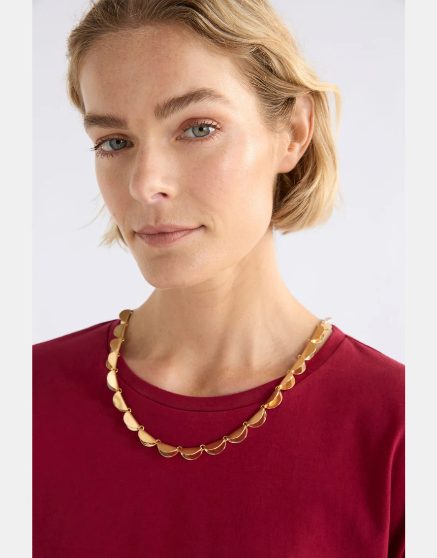 Elk Fossen Necklace in gold, featuring a delicate chain and elegant pendant, displayed on a neutral background.