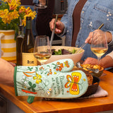 Blue Q oven mitt with colorful "Shitstorm" design, heat-resistant fabric for kitchen use.