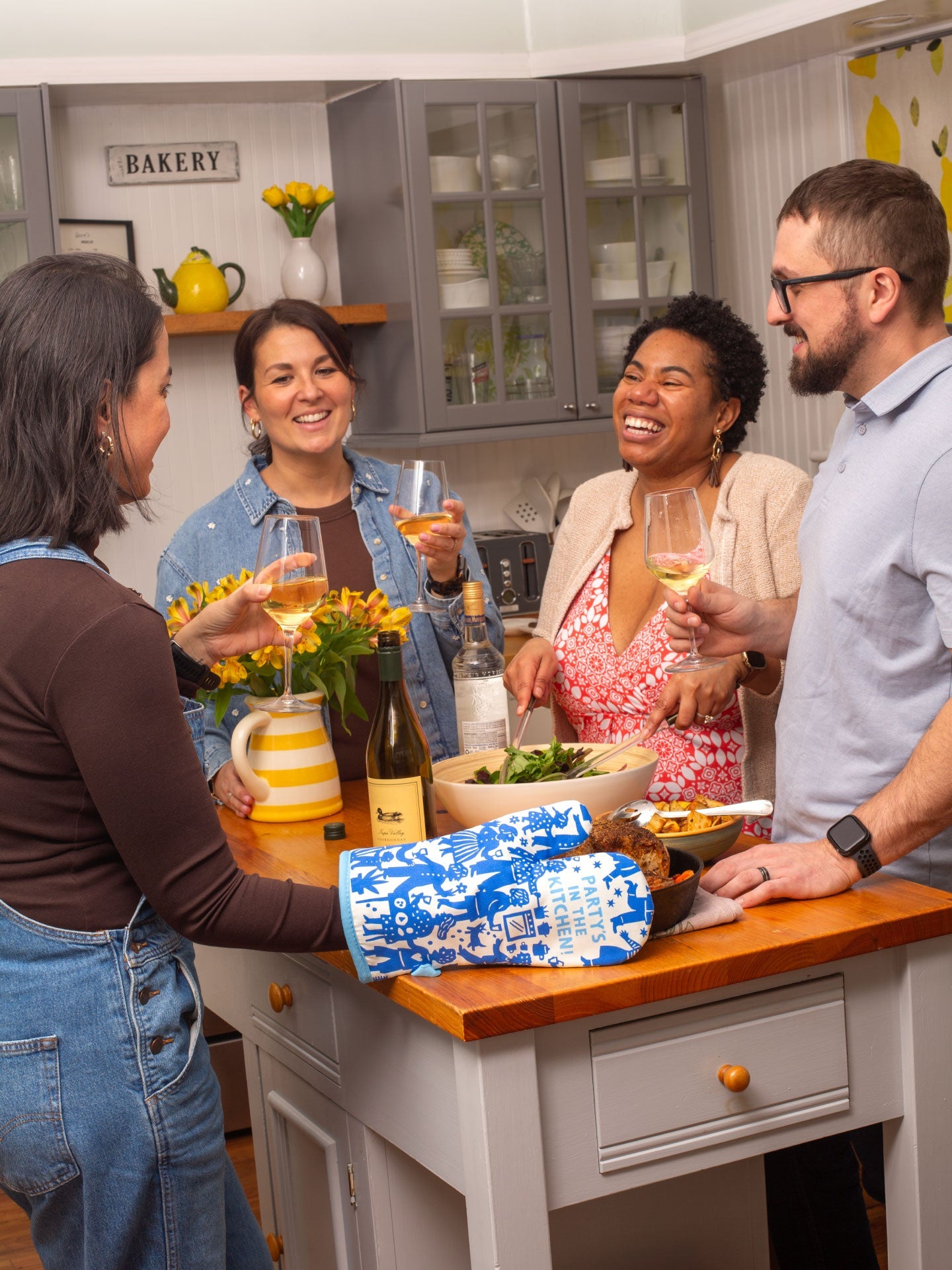 Blue Q oven mitt featuring colorful party in the kitchen design, made for safe handling of hot cookware.
