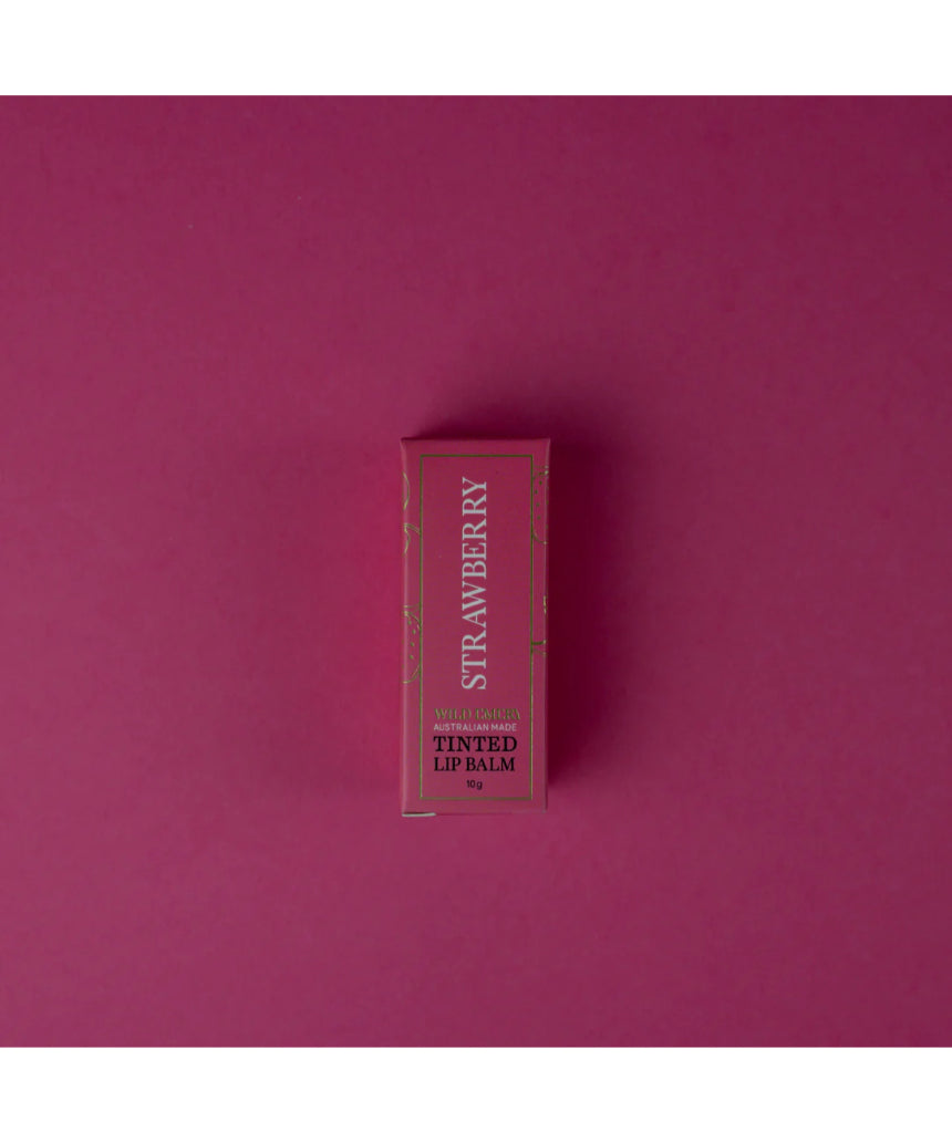 Wild Emery strawberry tinted lip balm in a sleek tube, showing the balm's pink hue and smooth texture.