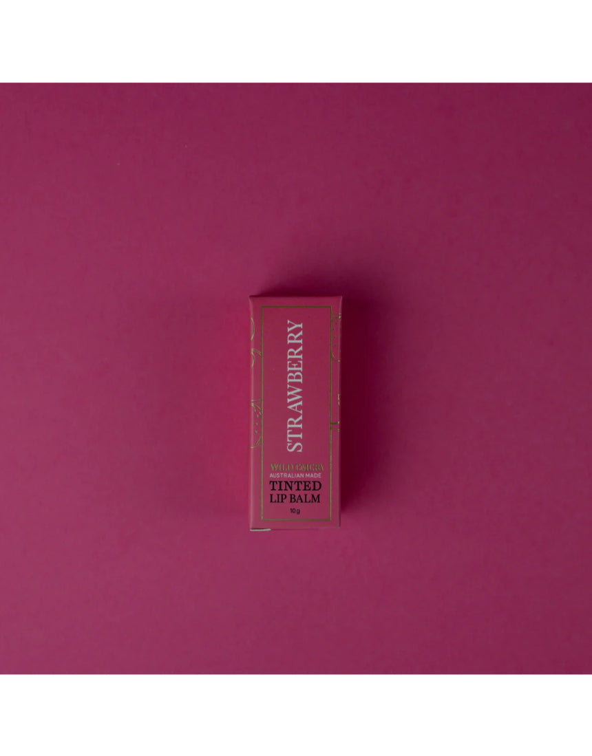 Wild Emery strawberry tinted lip balm in a sleek tube, showing the balm's pink hue and smooth texture.