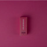 Wild Emery strawberry tinted lip balm in a sleek tube, showing the balm's pink hue and smooth texture.