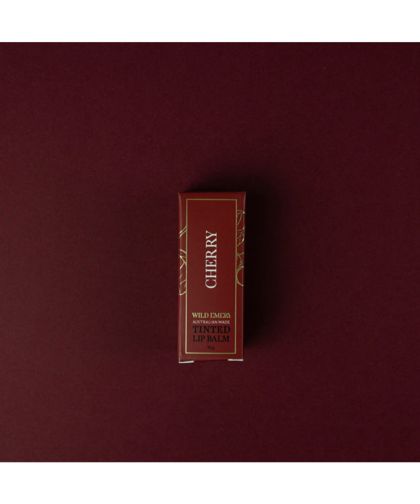 Cherry tinted lip balm by Wild Emery in a sleek tube, showing the smooth, glossy balm with a hint of cherry color.